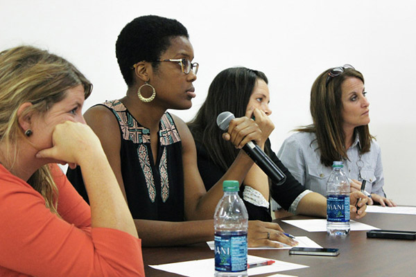 Four diverse ladies at a table engaged in a conversation with a microphone