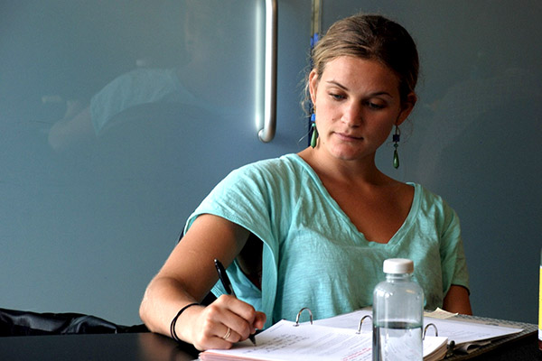Young woman dressed in a aqua shirt writing in her CO.STARTER binder