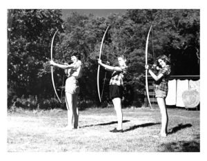Three Young women shooting archery outside